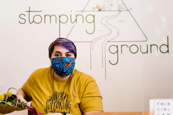 Person in mask in front of stomping ground sign